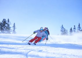 Row of male and female skiers skiing down snow covered ski slope, Aspen, Colorado, USA